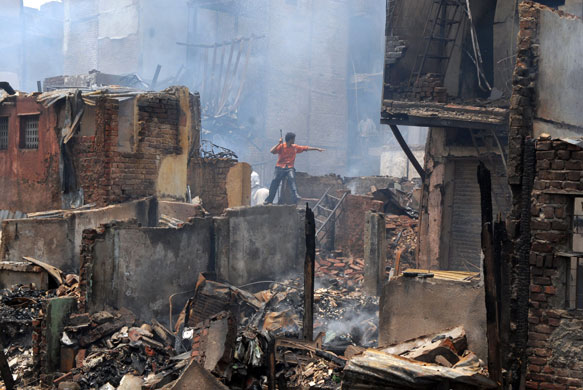 19 June 2009: Mumbai, India: A man looks for belongings in fire damaged Garibnagar slums