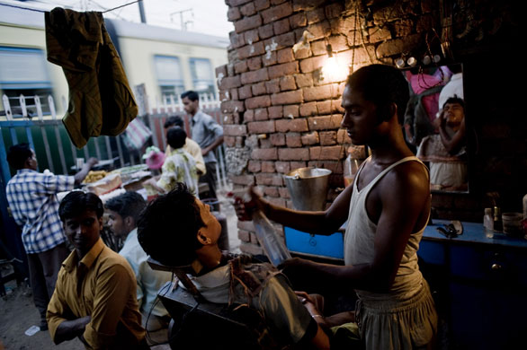 19 June 2009: New Delhi, India: A man is shaved by a street barber
