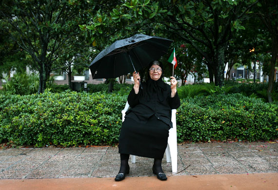 19 June 2009: Orlando, US: 82-year-old Manesar Kashani sits behind protestors