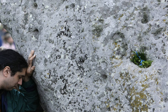 Stonehenge solstice: A man touches one of the stones during the summer solstice at Stonehenge