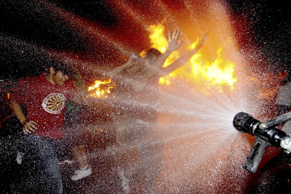 24 hours in pictures: A firefighter wets young people prior to their jump through a bonfire Spain
