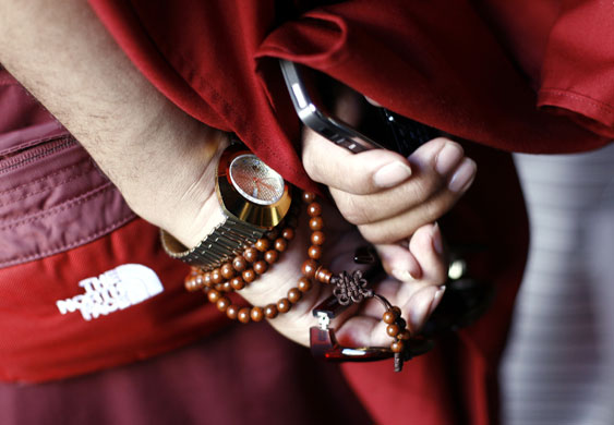 24 hours in pictures:  monk holds a mobile phone and sunglasses at the Jokhang Temple in Lhasa