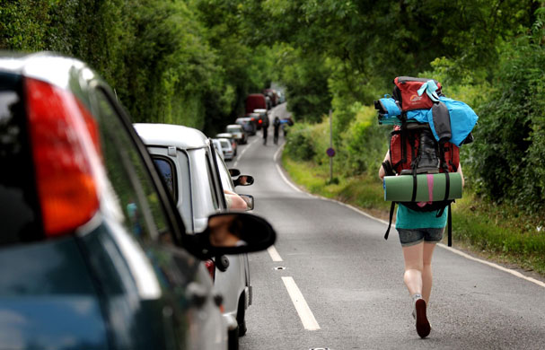 Glastonbury arrivals: A woman walks along the B3136 on her way to Glastonbury Festival