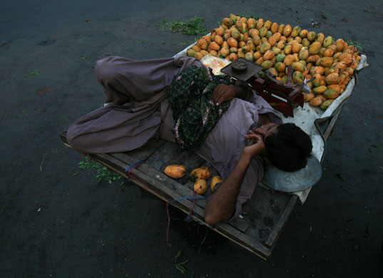 25 June 2009: Lahore, Pakistan: A man selling mangos sleeps on his cart