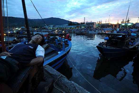 26 June 2009: Da Nang, Vietnam: A fisherman sleeps on his boat in a fishing port