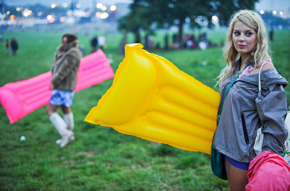 26 June 2009: Glastonbury, UK: Two girls walk through the site with blow-up airbeds