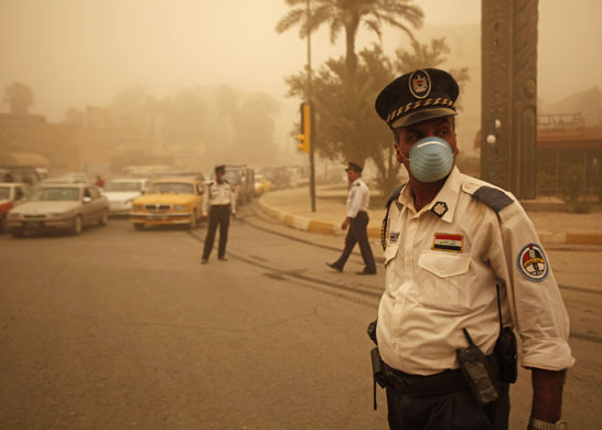 28 June 2009: Baghdad, Iraq: Policemen direct traffic during a sand storm