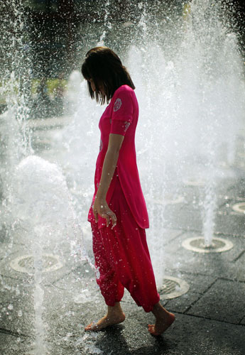 UK weather update:  student cools off in the fountains of Piccadilly Gardens