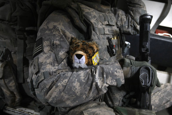 Iraq: A US soldier carries a stuffed toy to give to a child