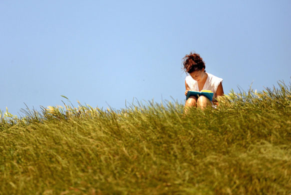Heatwave: A woman reads a book as people enjoy the sunshine on Primrose Hill, London