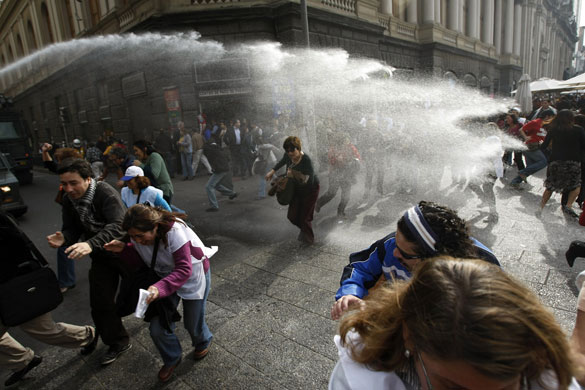 24 hours in pictures: Teachers run away from a police water cannon during a rally in Santiago
