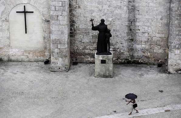 24 hours in pictures: A woman, holding an umbrella, walks in Havana