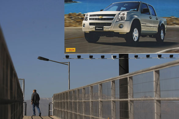 Week in Business: A pedestrian walks past a poster of a Chevrolet vehicle in Santiago