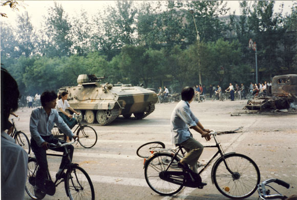 Tiananmen protests 1989: An armoured vehicle passes cyclists, Fuxing Road at Gongzhufen