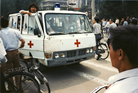 Tiananmen protests 1989: An ambulance carrying wounded people drives west from Tiananmen Square