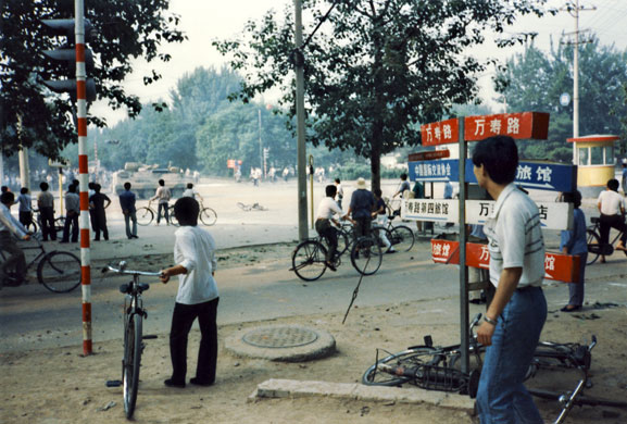 Tiananmen protests 1989: Civilians watch a military armoured vehicle drive by