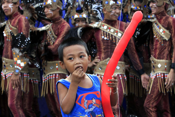 24 hours in pictures: Manila, Philippines: A boy eats as he watches performers