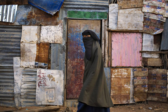 24 hours in pictures: Dadaab, Kenya: A veiled Somali refugee walks past a shack at Dagahaley camp