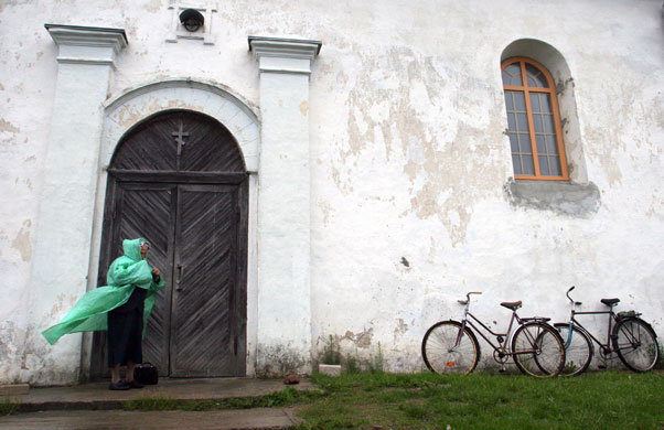 24 hours in pictures: A woman stands at the door of a church in the village of Noviy Sverjen