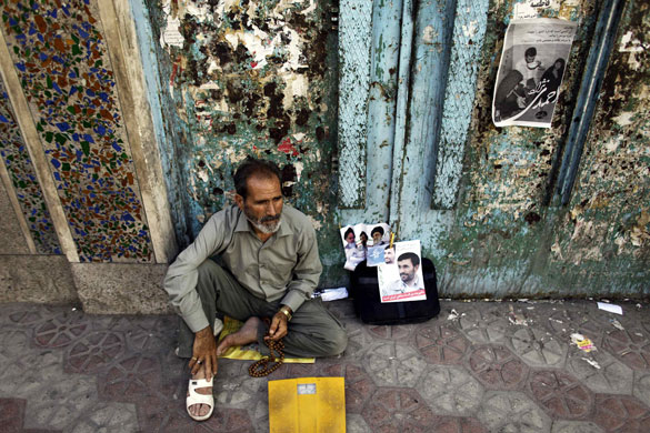 24 hours in pictures: A man sits beside pictures of Iranian President Mahmoud Ahmadinejad in Qom