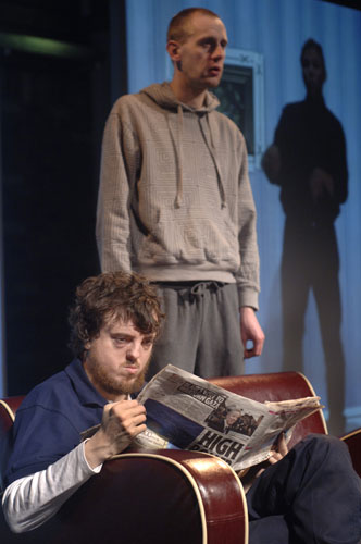 Performing & Disability: Two actors perform on stage, one sits reading a newspaper