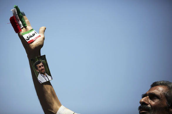 Iran elections: A supporter of Mahmoud Ahmadinejad looks at his picture on his arm