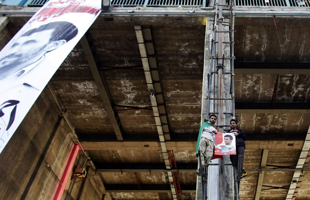 Iran elections: Supporters of Mahmoud Ahmadinejad climb at a pre-election gathering