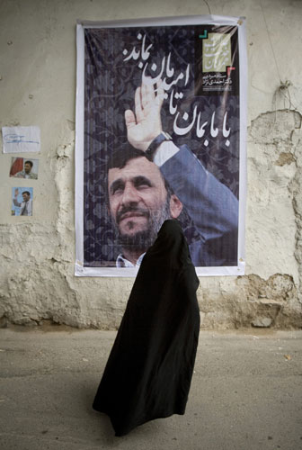 Iran elections: Woman stands in front of a President Ahmadinejad campaign banner in Tehran