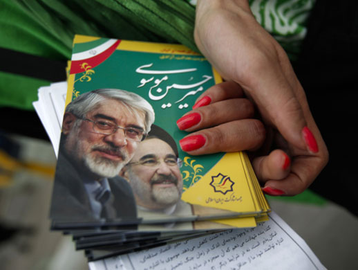 Iran elections: A supporter of Mir Hossein Mousavi distributes pictures at campaign rally 