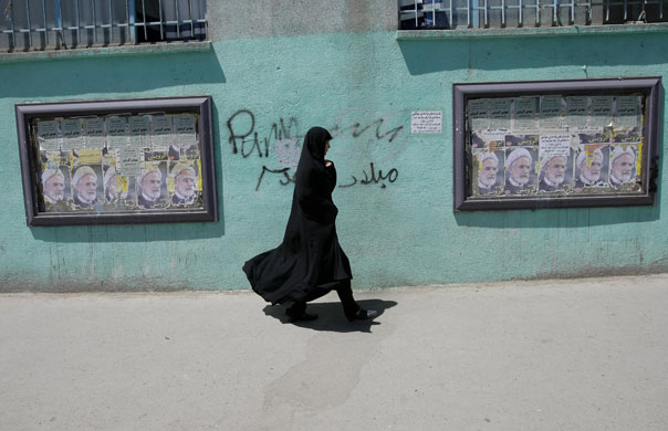 Iran elections: An Iranian woman walks past campaign posters of candidate Mehdi Karroubi