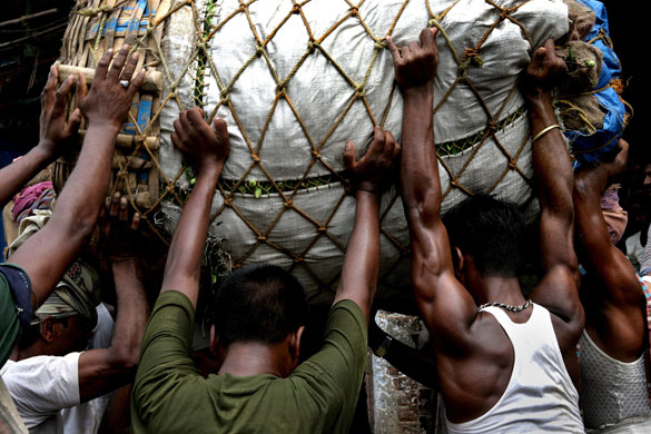 9 June 2009: Kolkata, India: Vendors try to unload a package of vegetables from a truck