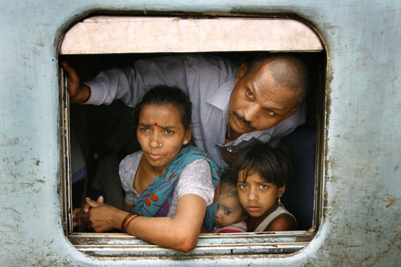 24hours in pictures: Passengers look at a crowd waiting to board a train India