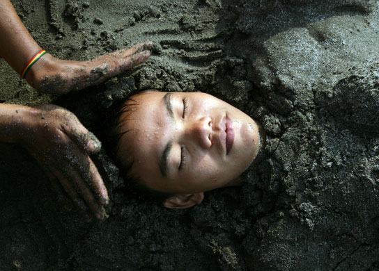 13 July 1009: : Jakarta, Indonesia: A boy is covered with sand at a beach