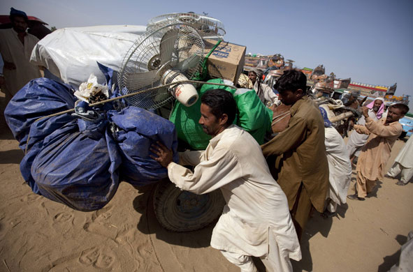 Refugees return to Swat: Internally displaced men push a horse cart with their belongings