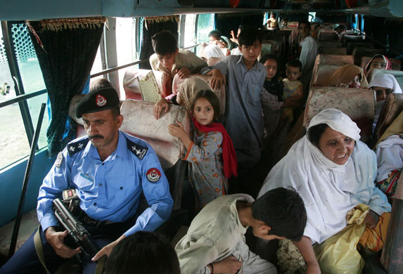 Refugees return to Swat: A policeman accompanies internally displaced families