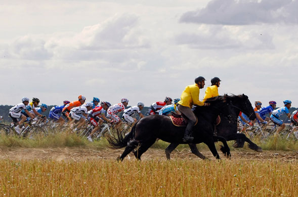 Tour de France Stage 10: Two horsemen gallop alongside the peloton