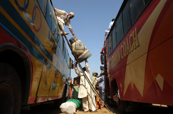 15 July 2009: Pakistan: People load their belongings onto a bus to return home