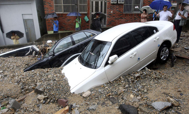 16 July 2009: Busan, South Korea: Residents look at cars affected by floodwater