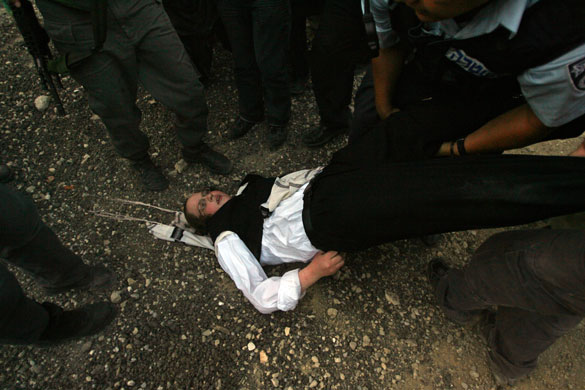 16 July 2009: Jerusalem, Israel: Border policemen carry an ultra-Orthodox Jew