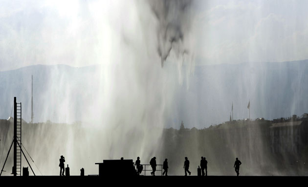 Week in Business: People enjoy a warm evening next to a fountain at Lake Geneva, Switzerland