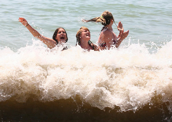 Heatwave: Three friends enjoy the surf of Brighton beach