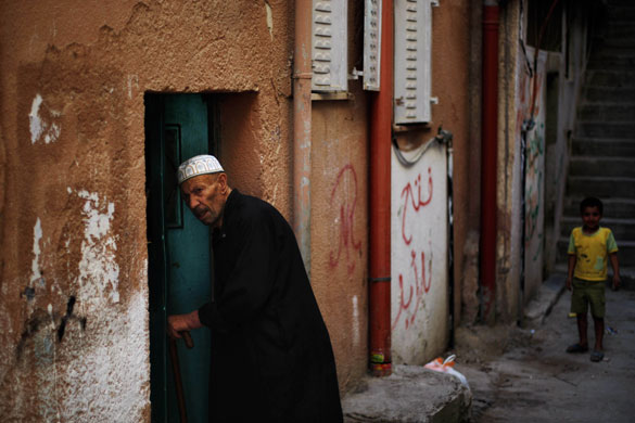 24hours in pictures: A Palestinian boy looks on as an elderly enters his house West Bank