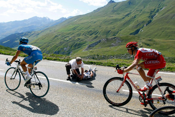 Tour de France stage 16: Riders cycle past Jens Voigt as he receives treatment