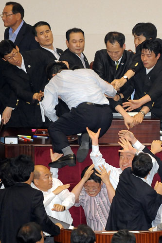 Korean lawmakers: An opposition legislator, centre, climbs on the parliament speaker's podium