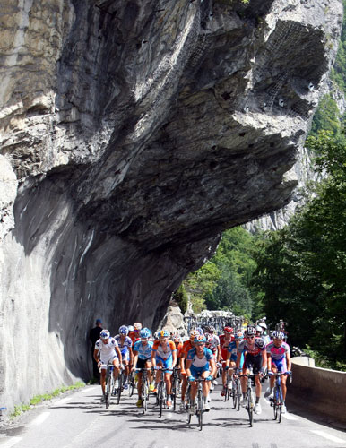 Tour de france stage 17: The pack of riders pass underneath an overhanging rock 