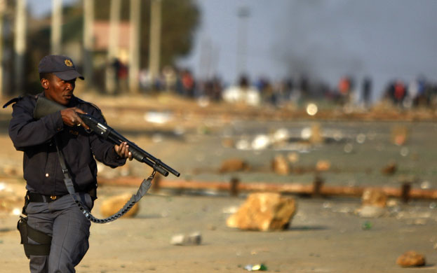 South Africa violence: A policeman keeps watch after protesters blocked roads in Siyathemba