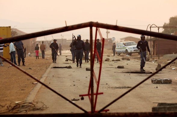 South Africa violence: Armed police walk down a street as riots break out in Balfour