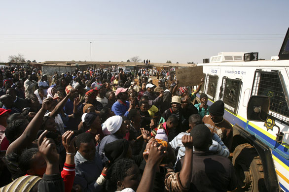 South Africa violence: Protesters surround a police vehicle as riots break out in Thokoza