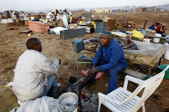 South Africa violence: Two men sit with their belongings during protests in Johannesburg