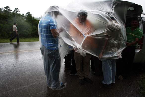 27 July 2009: Jacagalpa, Honduras: People protect themselves from the rain